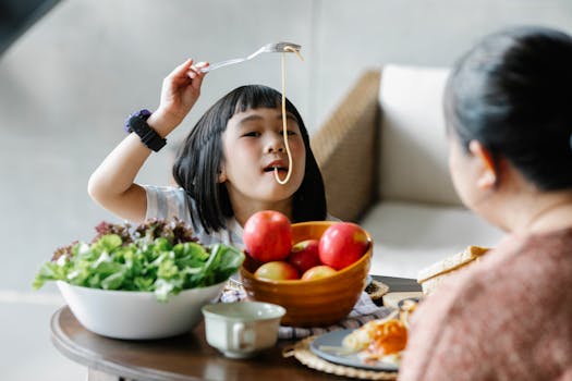 A child happily eating a bowl of salmon and vegetables